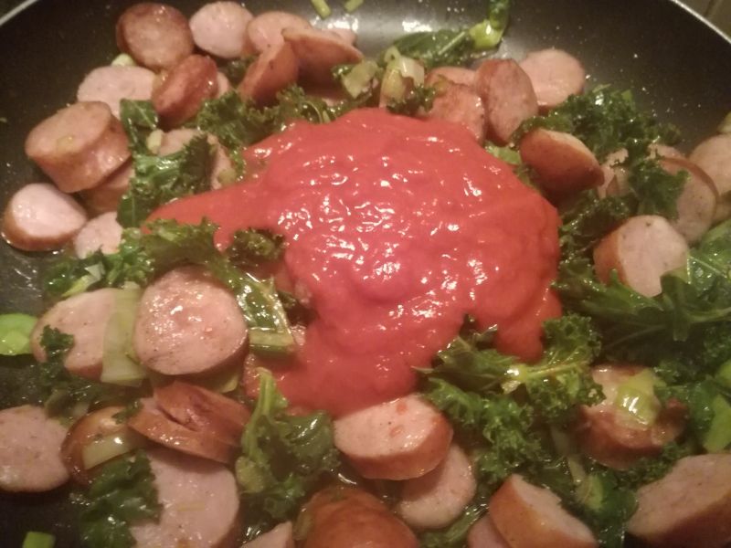 Duszona kiełbasa z jarmużem w sosie pomidorowym
