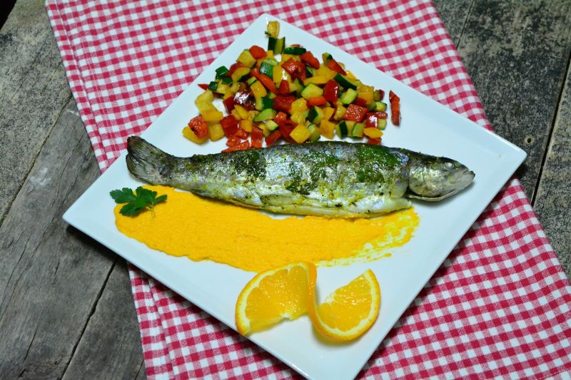 Pieczony pstrąg podany na pomarańczowym puree