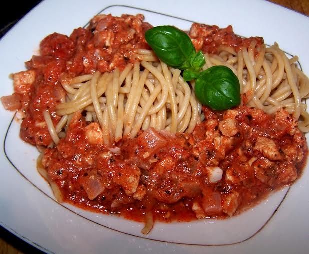 Razowe spaghetti w sosie z kurczaka i pomidorów.